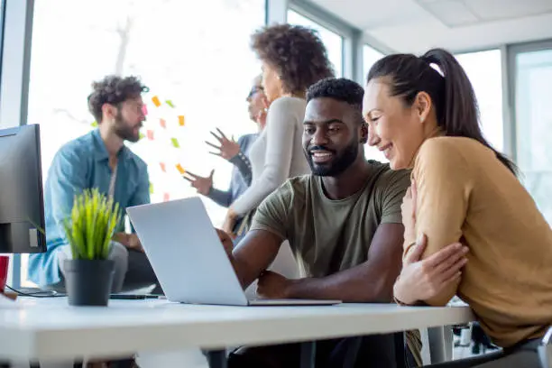 An image showing employees working together in a positive and collaborative environment at a real estate brokerage, helping you understand how to choose a real estate brokerage to work for based on company culture and environment.