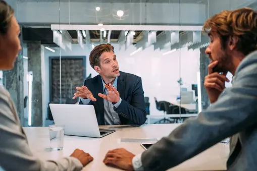 An image showing a group of realtors for first time home buyers discussing and negotiating the terms of a home purchase agreement.