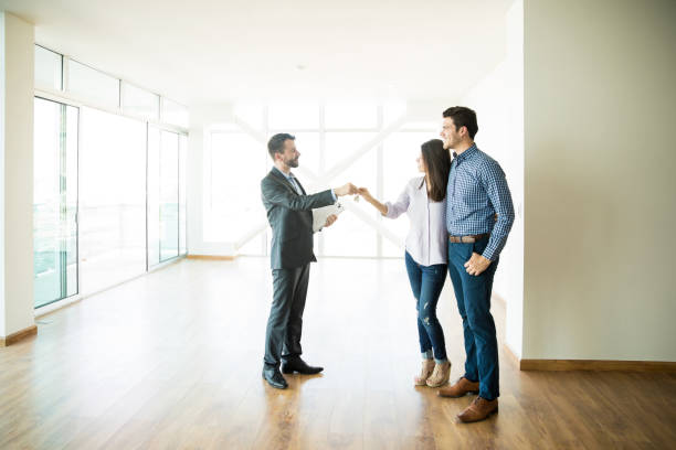 An image of a smiling real estate agent holding a set of keys, highlighting the benefits of hiring a real estate agent during the home buying process.