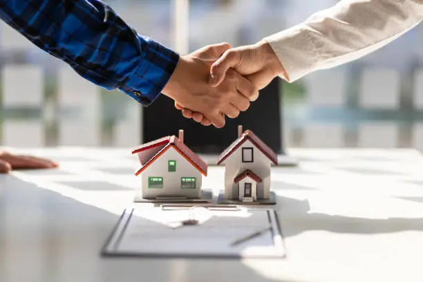 A real estate agent and a builder shaking hands and smiling