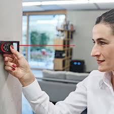 A real estate agent using a laser distance measure to measure a room